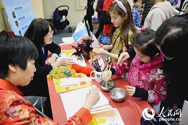 义工老师们在教中外小朋友们学习如何使用筷子。(张大卫 摄)