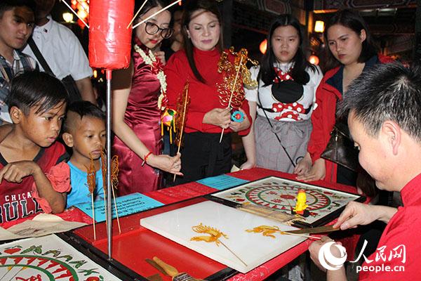 菲律宾国家公园管理处处长比以蒙特、孔院院长梁广寒体验糖画。