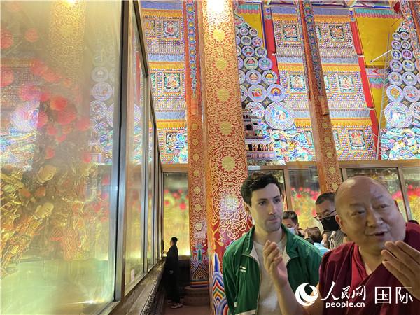 7月25日,省级非物质文化遗产项目塔尔寺酥油花的代表性传承人朋措坚参(右)在塔尔寺酥油花馆讲解酥油花的制作过程。人民网 谢莹摄