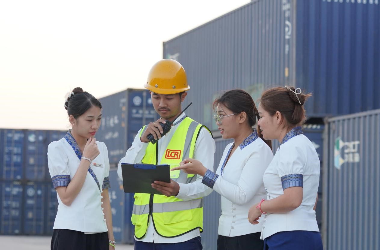 万象南站货运值班员陈尼啦(左一)与同事在一起讨论工作。老中铁路有限公司供图