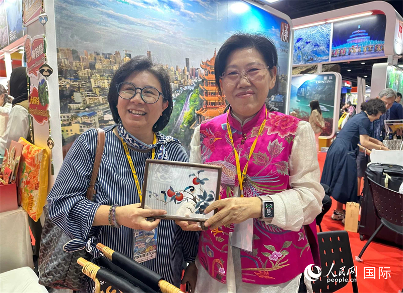 中国“大冶刺绣”传承人刘小红（右）参加泰国国际旅游展，向观众介绍中国非遗刺绣针法。人民网记者 简承渊摄