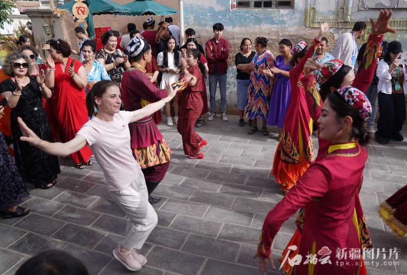 5月24日,在库车市龟兹小巷,交流营嘉宾和库车演员们共舞。