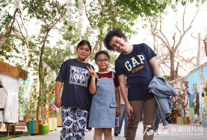 5月24日,在库车市龟兹小巷,土耳其《自由报》国际新闻主编内杰德·布拉克·奥兹尤尔特跟当地两名小朋友友好交流后合影留念。