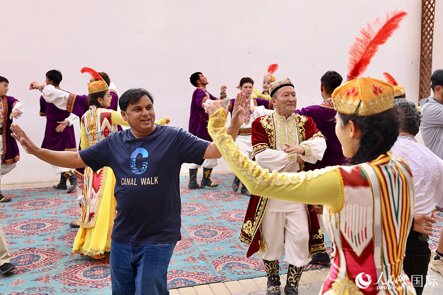 5月24日，上合组织国家青年文化交流营的青年们走进龟兹小巷，感受新疆生活。以上图为龟兹小巷内，中外青年们在一起跳舞。人民网记者 蒋雨师摄