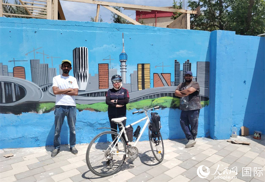 一位街头骑行者和艺术家在壁画墙前合影。人民网 伊纳斯·易卜拉欣摄