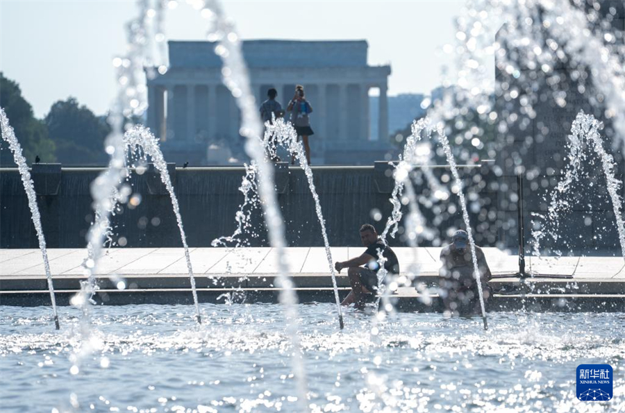 6月23日，在美国首都华盛顿，人们在一处喷泉纳凉。新华社记者 胡友松 摄