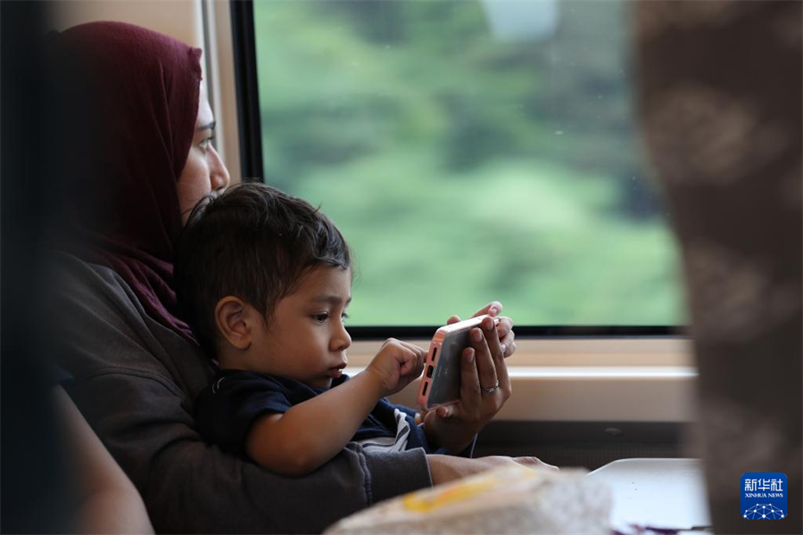 6月19日，一名乘客带孩子坐在行驶中的雅万高铁车厢内。新华社记者 岑云鹏 摄