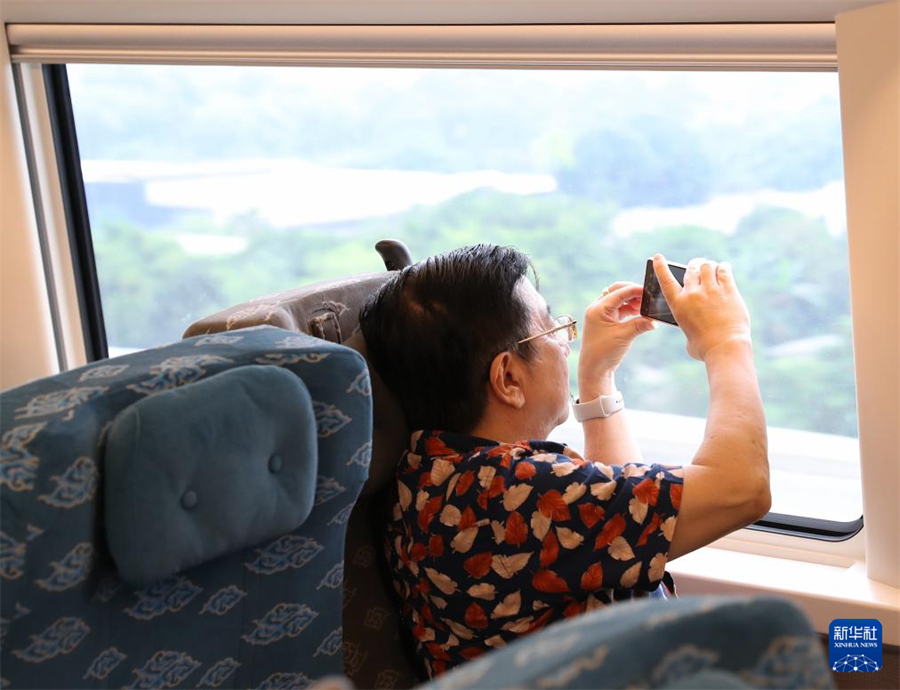 6月19日，一名乘客在行驶中的雅万高铁车厢内拍摄沿途风景。新华社记者 岑云鹏 摄