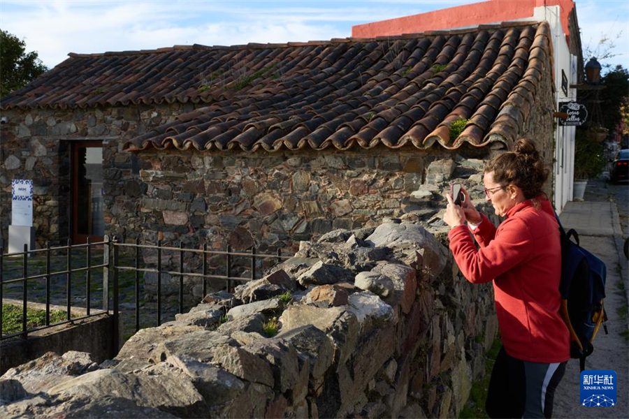 6月25日，一名女子在乌拉圭科洛尼亚的老城区拍摄历史建筑。新华社记者 孟鼎博 摄