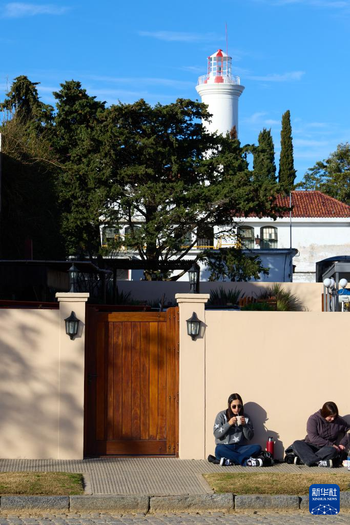 6月25日，两名女子坐在乌拉圭科洛尼亚的老城区街头。新华社记者 孟鼎博 摄