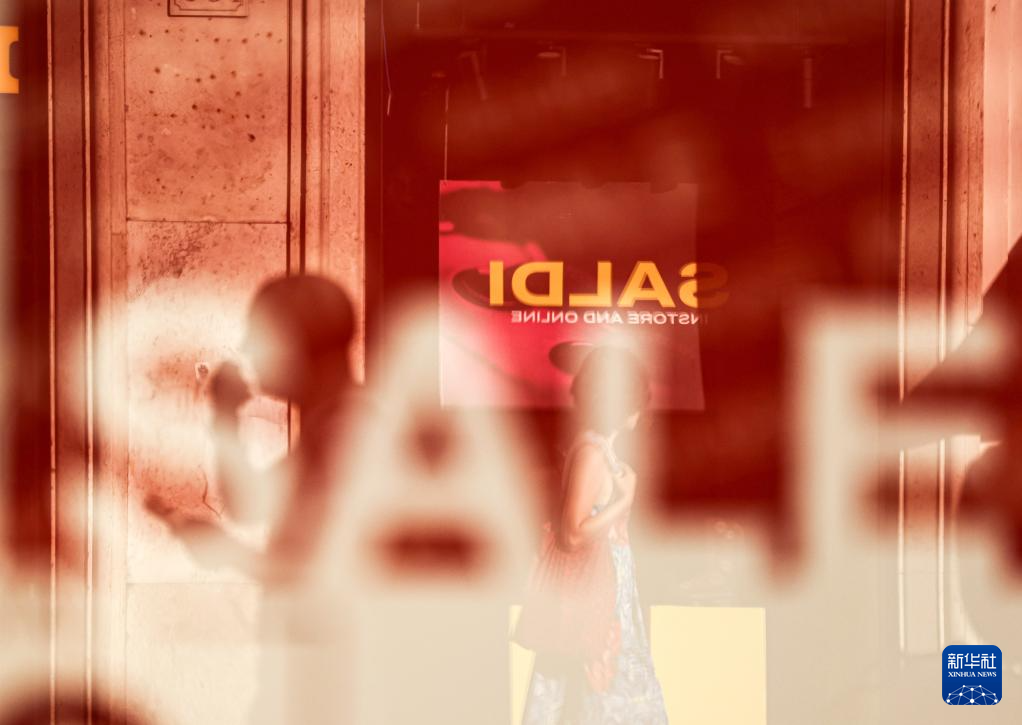 7月5日，在意大利罗马，人们经过一处商店橱窗。新华社记者 李京 摄
