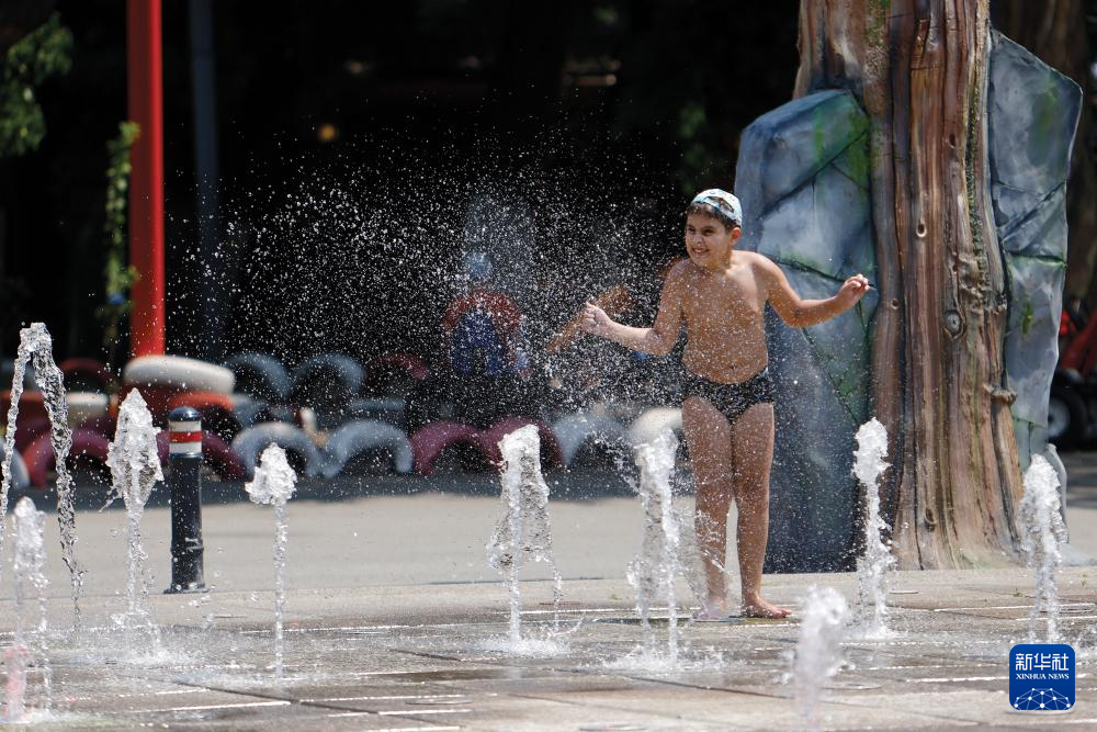 7月8日，在罗马尼亚首都布加勒斯特，儿童在喷泉中纳凉。新华社发（克里斯泰尔摄）