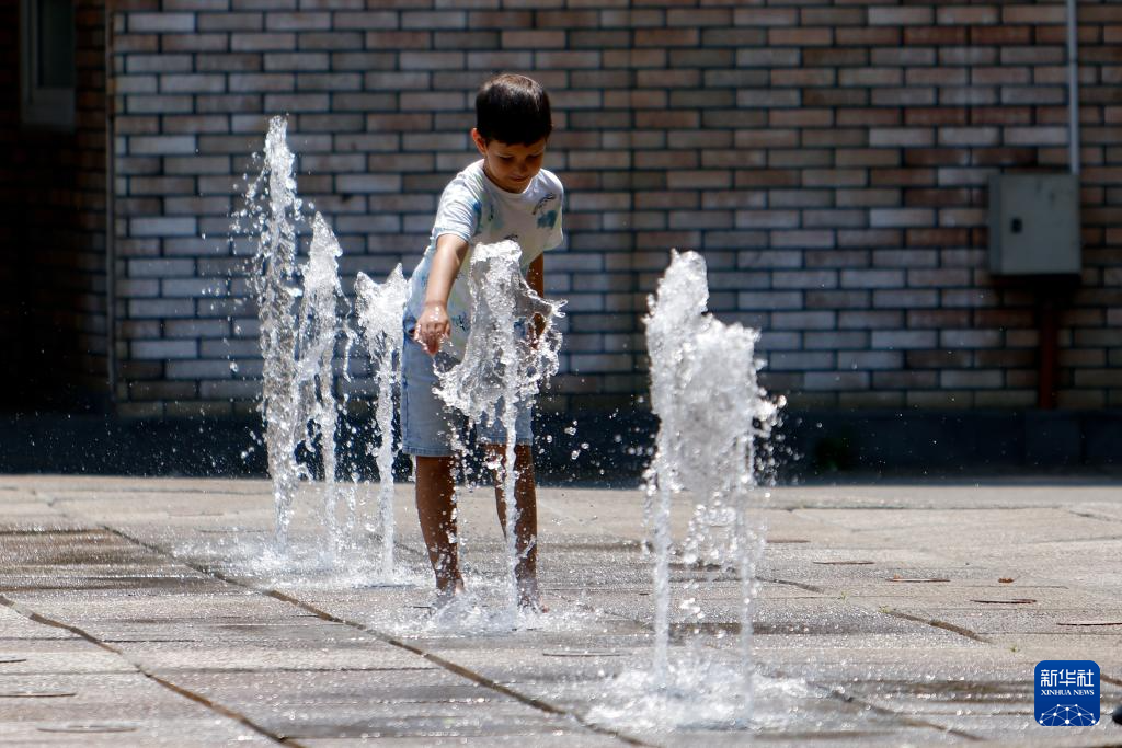 7月8日，在罗马尼亚首都布加勒斯特，儿童在喷泉中纳凉。新华社发（克里斯泰尔摄）