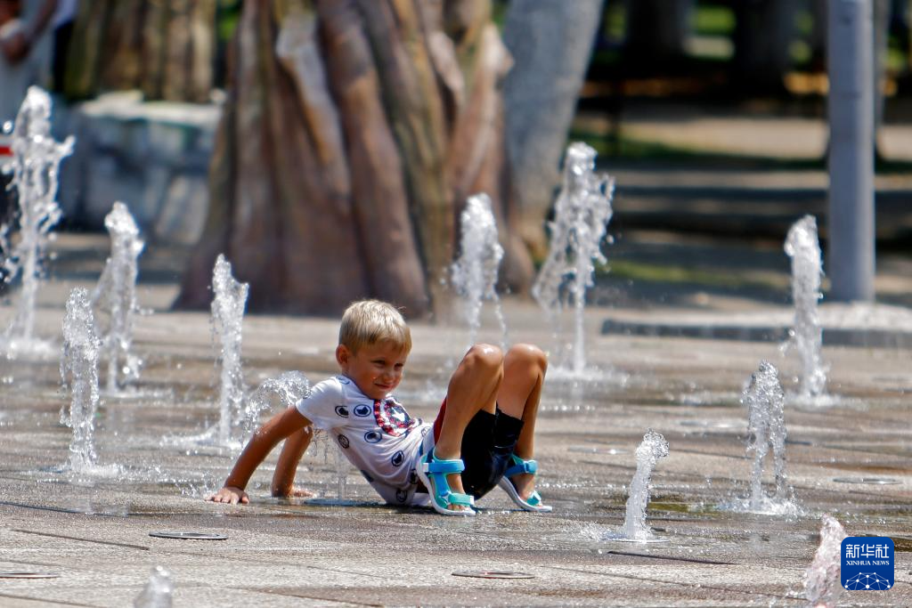 7月8日，在罗马尼亚首都布加勒斯特，儿童在喷泉中纳凉。新华社发（克里斯泰尔摄）