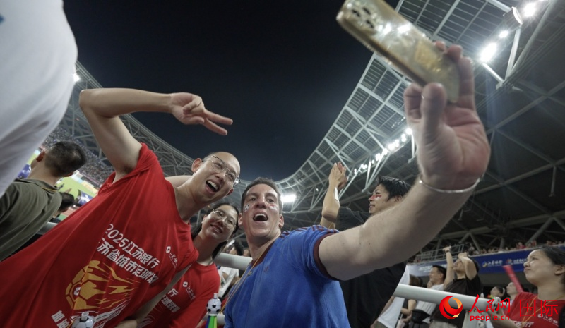 西班牙小伙湖长明在“苏超”现场和球迷合影。人民网记者 苏缨翔摄