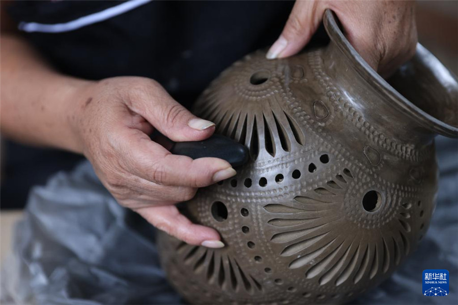 9月14日，在墨西哥瓦哈卡州的圣巴托洛科约特佩克市，一名黑陶手工艺者给陶罐进行抛光。新华社记者 李梦馨 摄