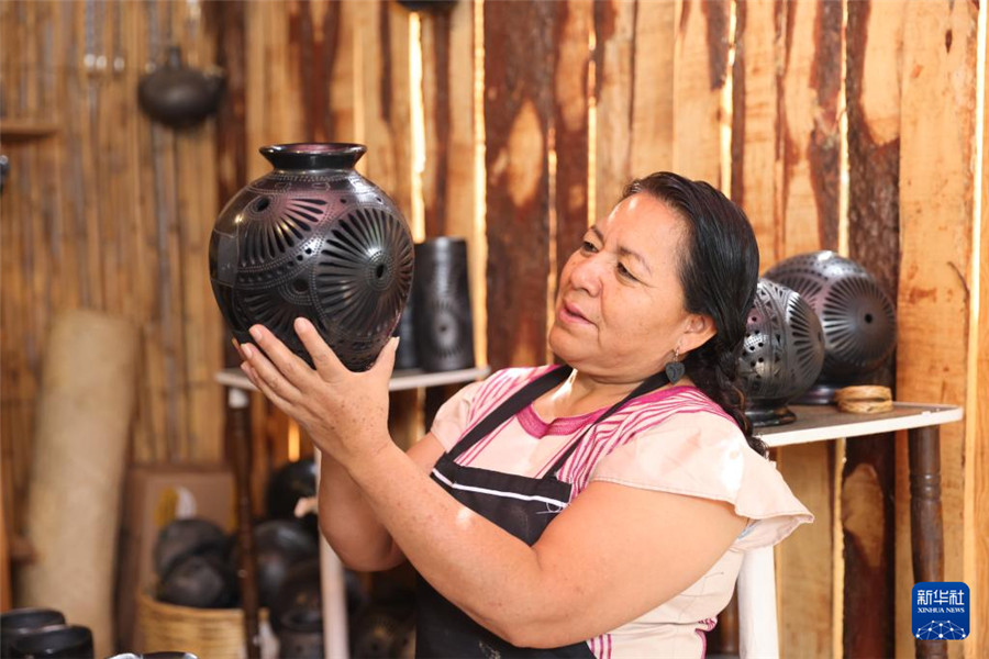 9月14日，在墨西哥瓦哈卡州的圣巴托洛科约特佩克市，黑陶手工艺者检查自己的作品。新华社记者 李梦馨 摄