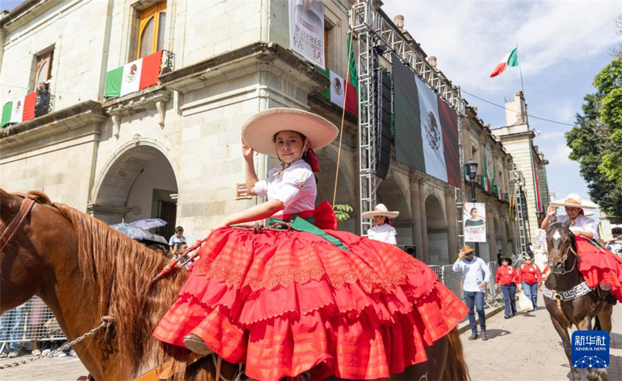 9月16日，在墨西哥瓦哈卡州的瓦哈卡市中心，身着传统民族服装的女孩骑马参加独立日庆祝活动。新华社记者 李梦馨 摄