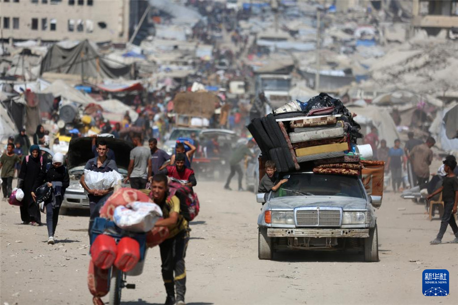 9月18日，在加沙城以西的沿海公路上，人们运载着生活用品，汇入人潮向南撤离。新华社发（里泽克·阿卜杜勒贾瓦德摄）