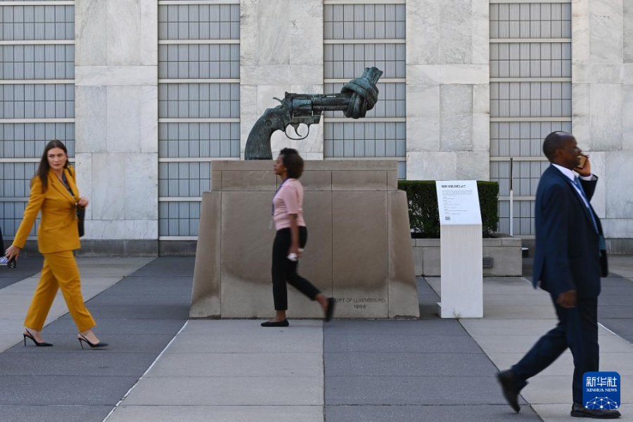 9月18日，在位于纽约的联合国总部，人们从“打结的手枪”雕塑前走过。新华社记者 李睿 摄