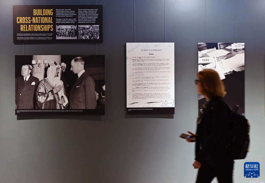 9月18日，在位于纽约的联合国总部，一名女子从“重振旧金山精神”展览的《联合国宪章》序言原始手稿图片（中）前走过。新华社记者 李睿 摄