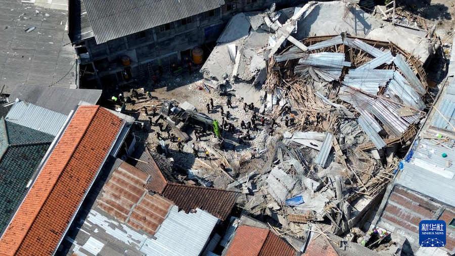 10月4日，救援人员在印度尼西亚东爪哇省诗都阿佐县的学校建筑物倒塌事故现场搜救（无人机照片）。