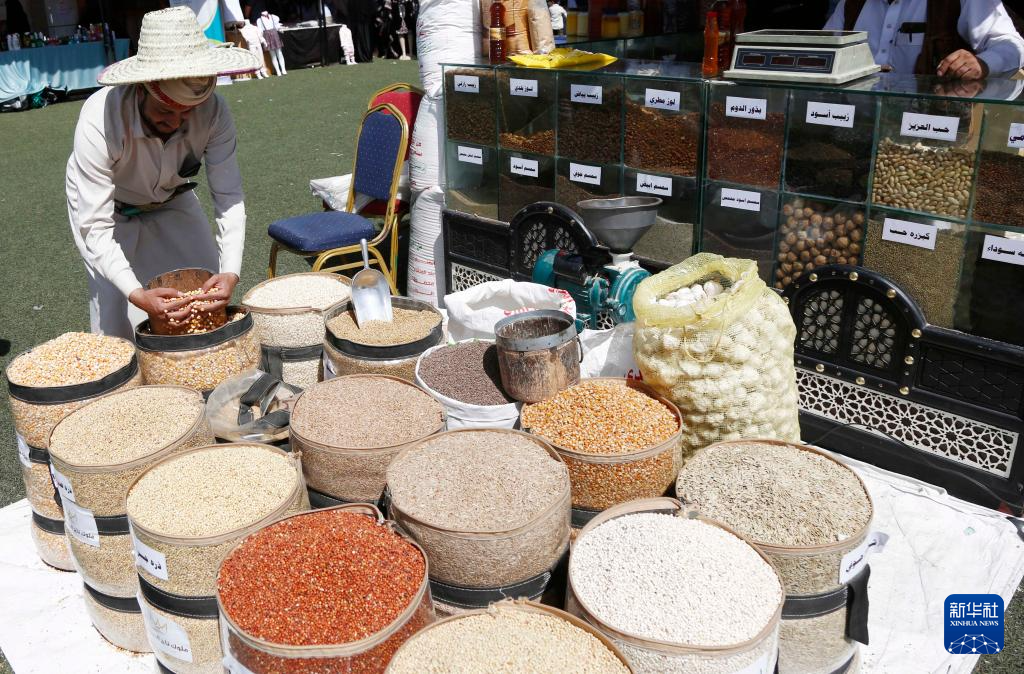 10月6日，在也门首都萨那，一名商贩在展会上展示本地生产的谷物。新华社发（穆罕默德摄）