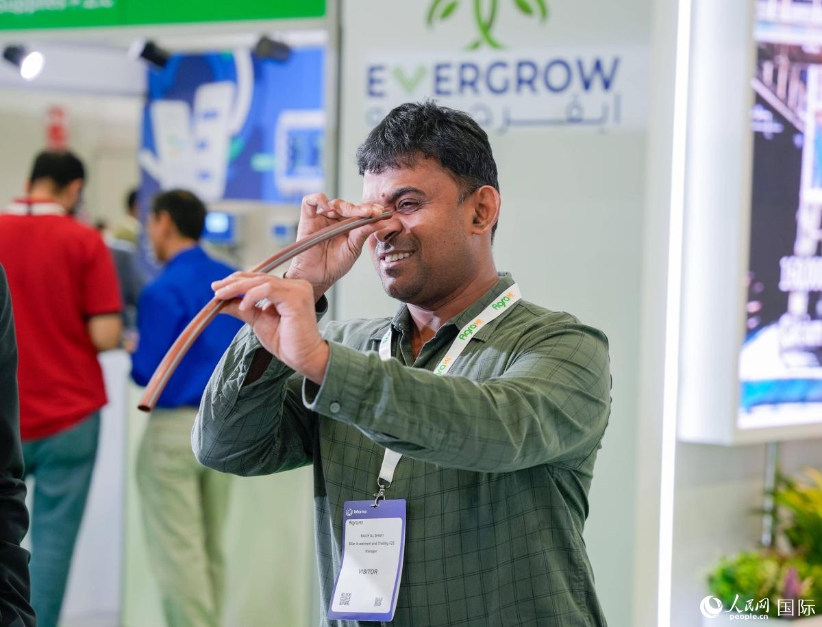 一名参展观众在了解滴灌用水管。人民网 塔里克·易卜拉欣摄