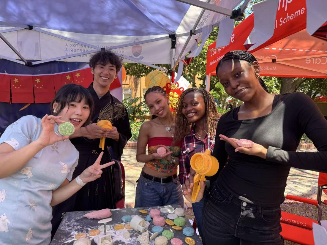 学生们拿着自己手作的月饼与中国教师张玥、王清超合影。南非中国文化中心孔子课堂供图