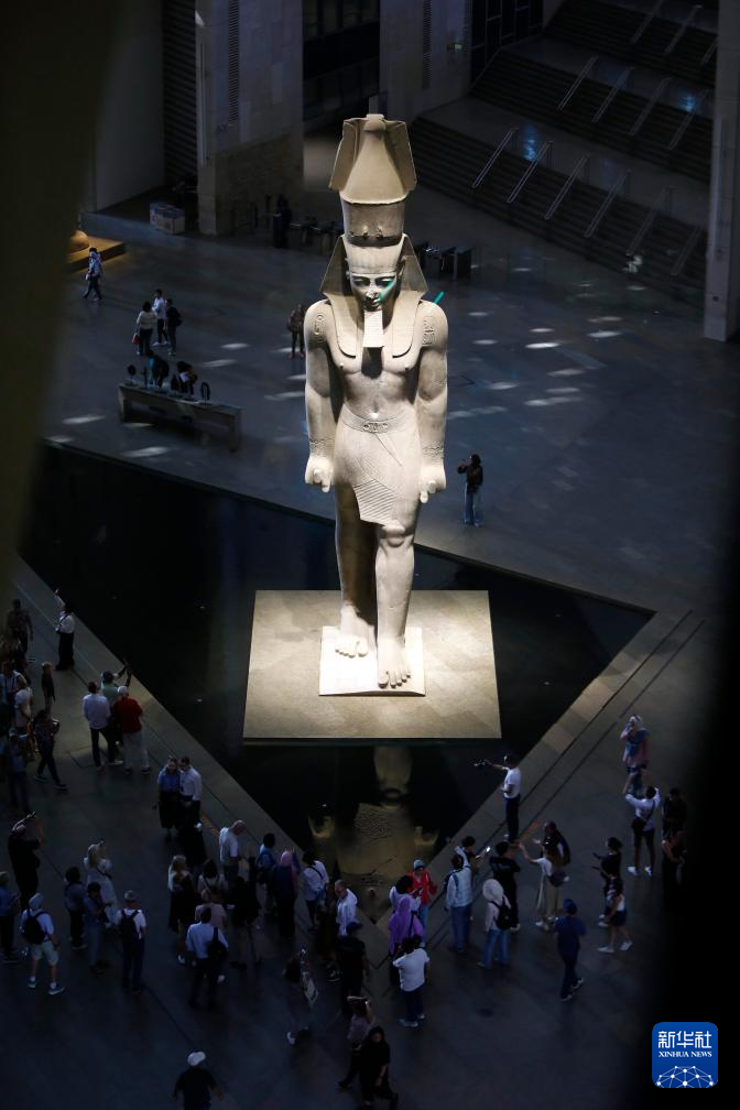 10月14日，在位于埃及吉萨省的大埃及博物馆，游客在古埃及法老拉美西斯二世的巨像旁参观。新华社发（艾哈迈德·戈马摄）