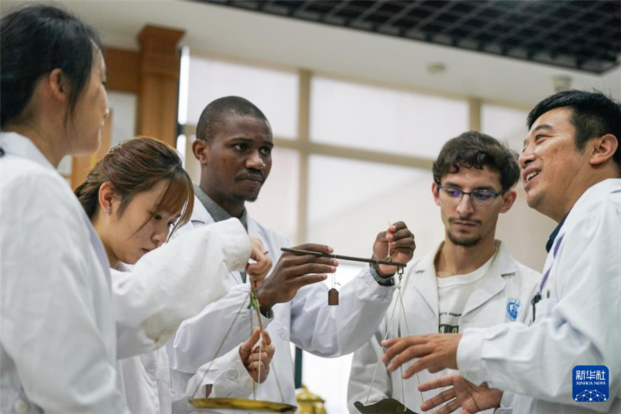 10月16日，安徽中医药大学老师潘银星（右一）带领外国学生学习秤的使用方法。新华社记者 杜宇 摄