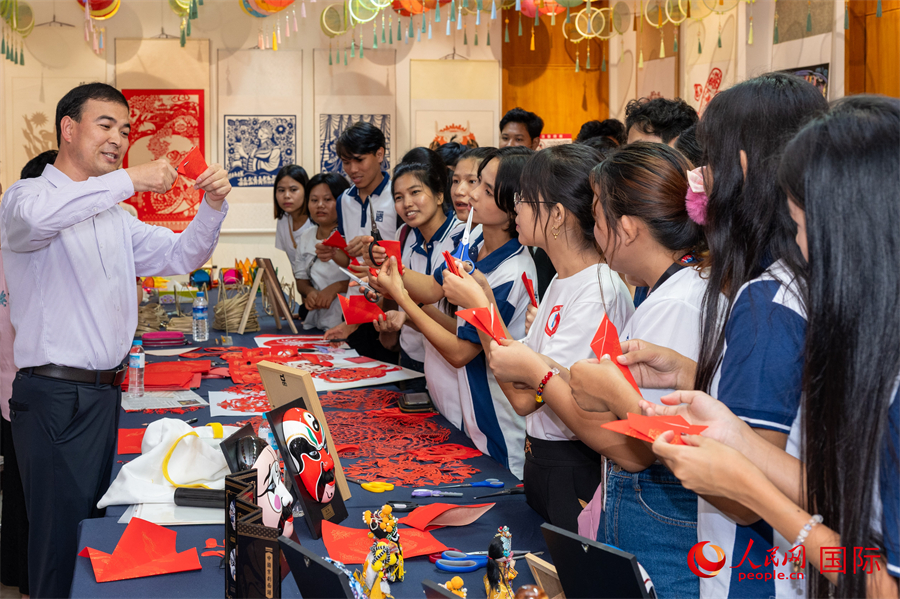 甘肃广河剪纸非遗代表性传承人马俊在活动现场与当地学生互动。人民网记者 谢佳君摄