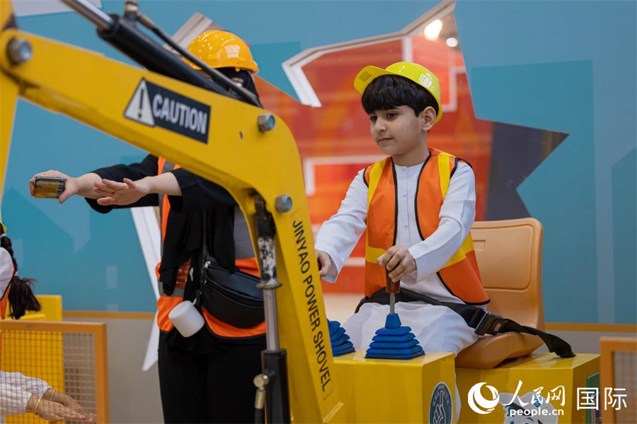一名儿童在体验挖掘机。人民网 塔里克·易卜拉欣摄