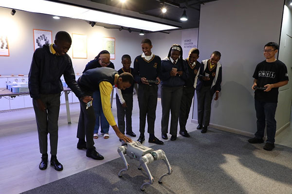 南非学生在中国工作人员的指导下操作机器狗。人民网记者 戴楷然摄