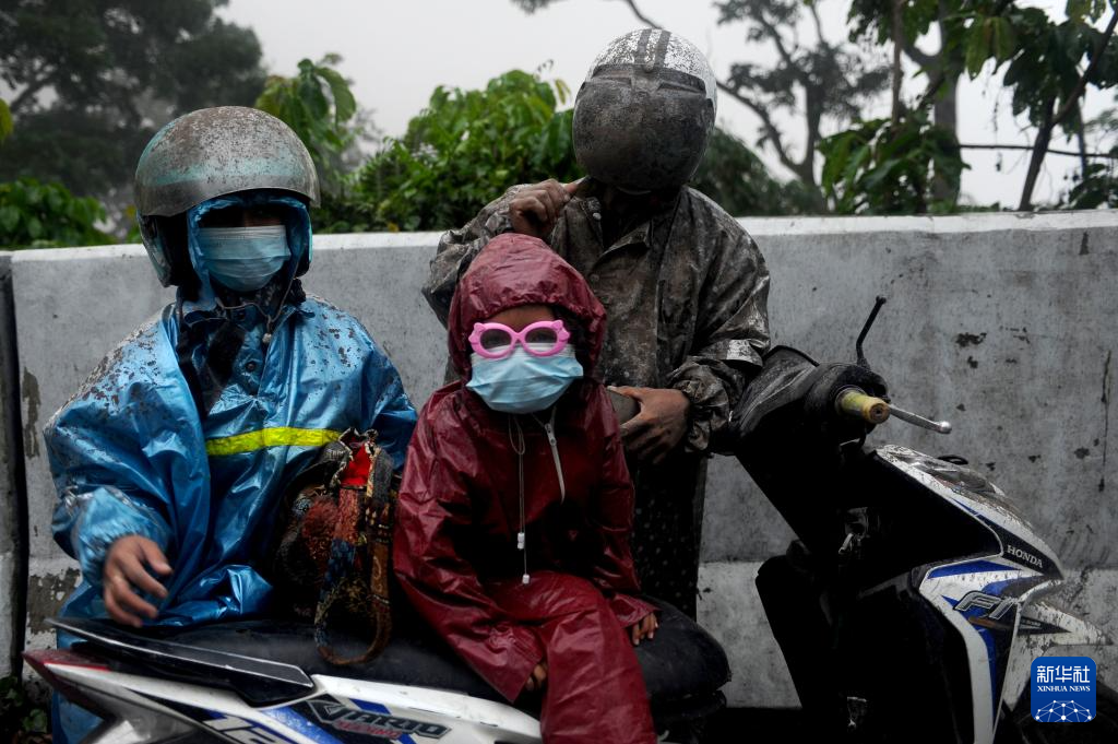 11月21日，在印度尼西亚东爪哇省，人们穿着雨衣冒着火山灰出行。新华社发（萨赫兰·库尔尼亚万摄）