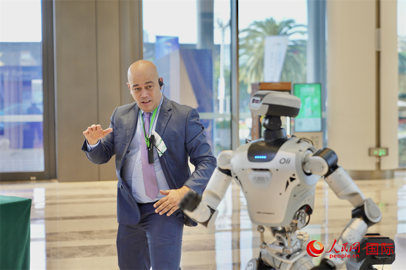 采风团成员在“大湾区—东盟人工智能前沿科技交互体验” 主题展上与机器人互动。人民网记者 许峥摄