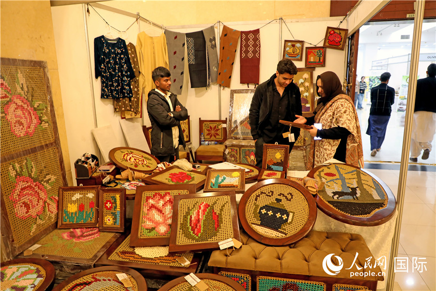 参观者在一家手工艺品展位前了解情况。人民网记者 赵益普摄
