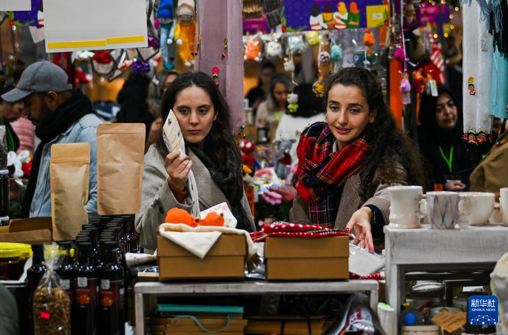 12月17日，顾客在土耳其伊斯坦布尔加拉塔港钟楼广场新年购物节上选购商品。新华社记者 刘磊 摄