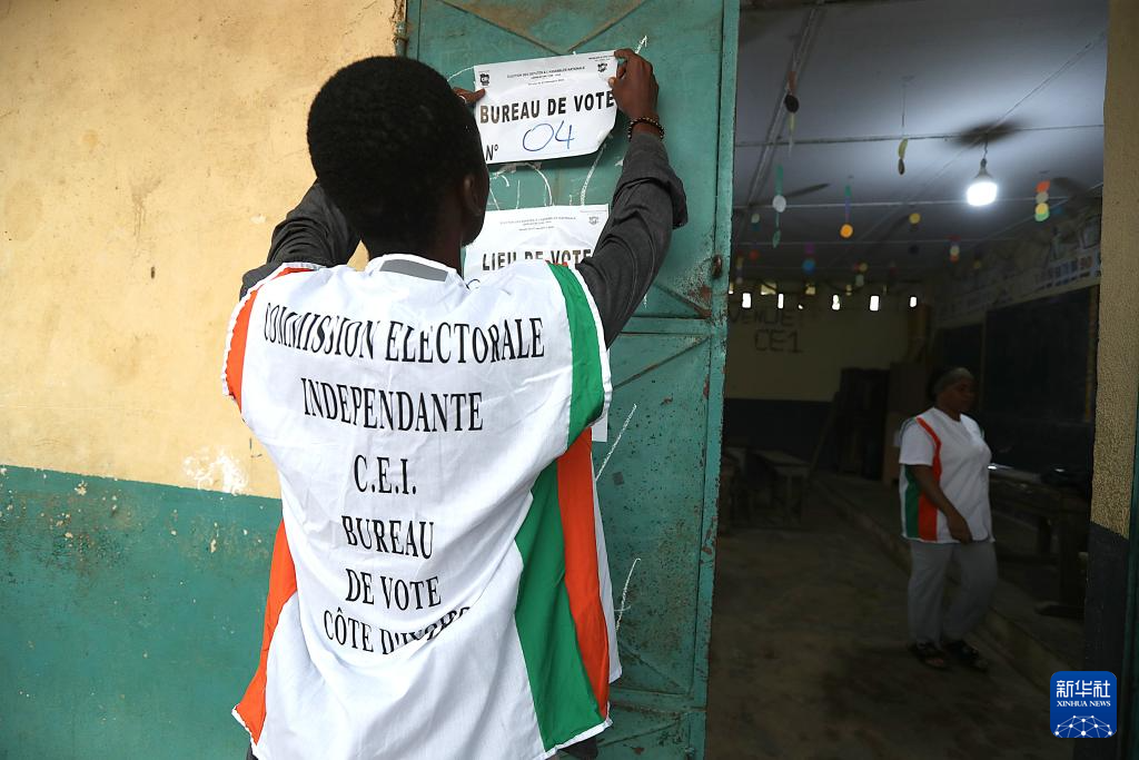 12月27日，在科特迪瓦经济首都阿比让的一处投票站，一名工作人员张贴投票站信息。新华社发（伊万·宋摄）