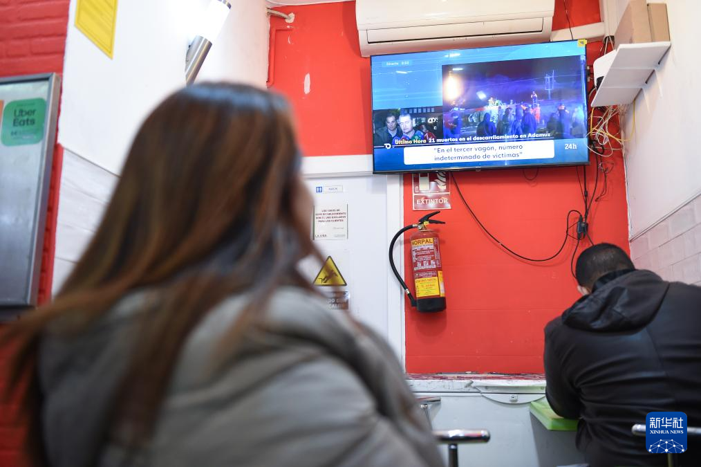 1月19日，人们在西班牙马德里一家餐厅内观看高铁脱轨相关新闻。