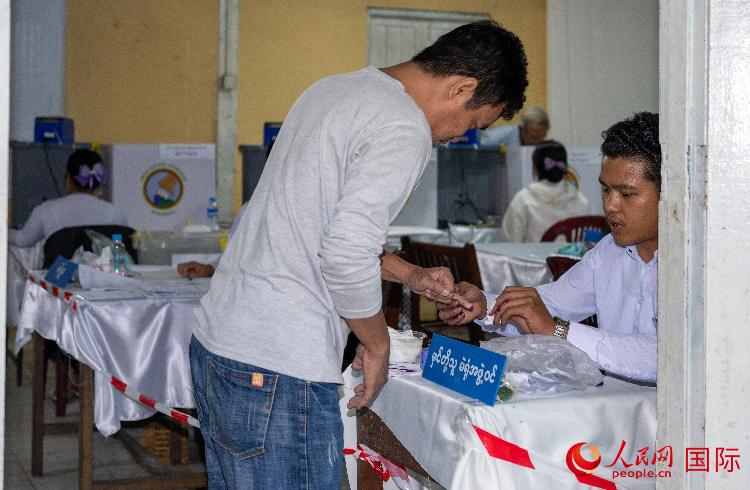 1月25日，一位投完票的仰光选民在工作人员指引下将小指染色。人民网记者 谢佳君摄