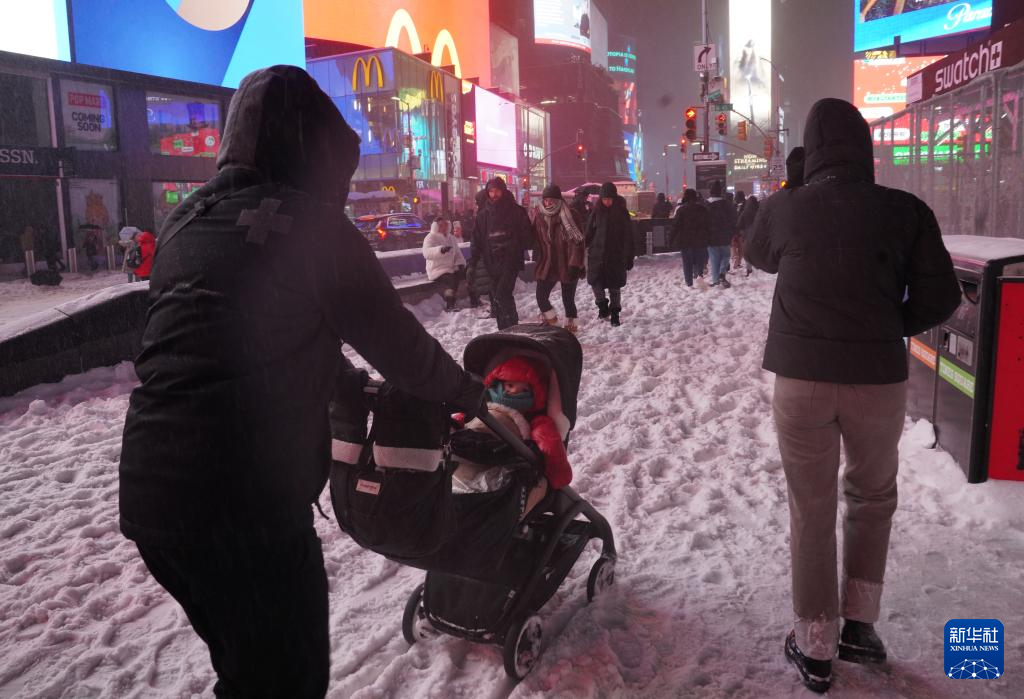 1月25日，在美国纽约时报广场，人们在雪中行走。新华社记者 张凤国 摄