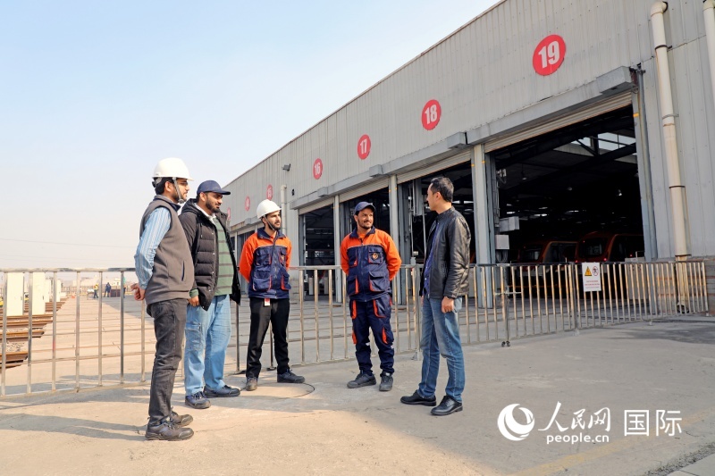 在橙线地铁车辆基地，中巴工作人员正在交流车辆维护经验。橙线地铁的运营维护工作由北方国际合作股份有限公司、广州地铁集团、巴基斯坦大宇快运集团组成的联营体共同承担。人民网记者 赵益普摄