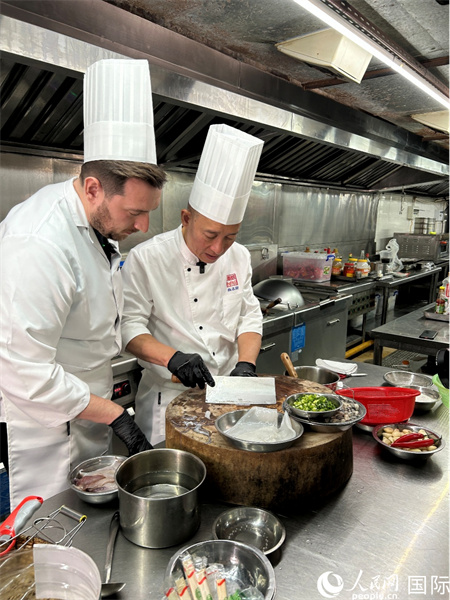 广东汕头,人民网外专柯明可向陈志毅师傅(右一)学习烹饪技艺。人民网 王潇平摄