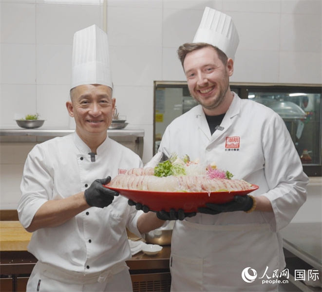 广东汕头,人民网外专柯明可与陈志毅师傅(右一)展示生鱼佳肴。人民网记者 刘宁摄