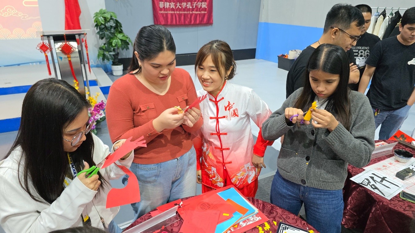 菲克拉克自由港区移民局职员在中国文化展台前体验剪纸民俗艺术。菲大孔子学院供图