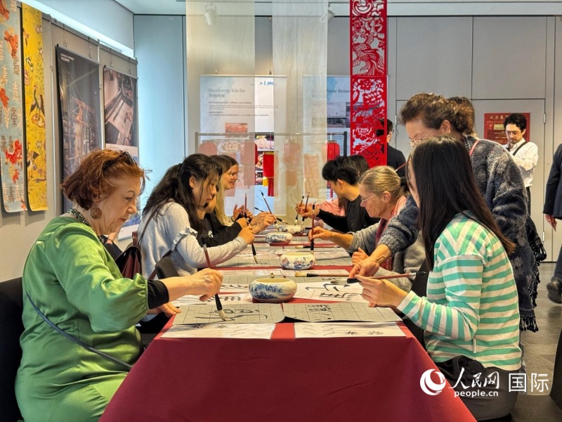 来宾们在练习书法，感受汉字书法之美。人民网实习生 赵宏笙摄