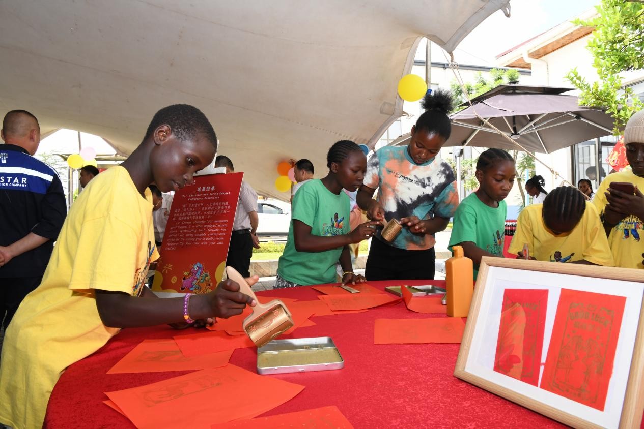 中企日前举办春节欢庆活动，当地社区儿童街舞团表演者在游园会现场体验中国传统拓印。中国路桥非洲之星铁路运营公司供图