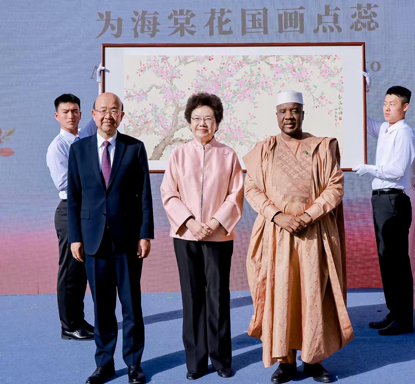 中国宋庆龄基金会主席李斌（中）与中国政府非洲事务特别代表刘显法（左）、非盟驻华代表巴赫（右）一起为此次活动新创作的国画《春满乾坤》上点落花蕊。 中国宋庆龄基金会供图