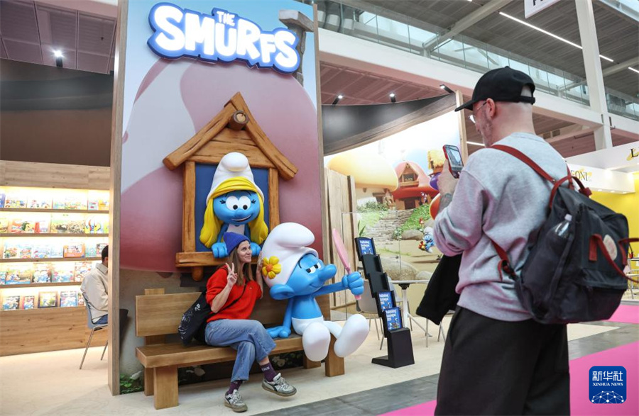 4月13日，在意大利博洛尼亚举行的博洛尼亚国际童书展上，观众与“蓝精灵”卡通形象合影。新华社记者 王楷焱 摄